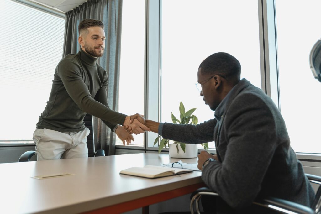 Two professionals shaking hands in a modern office, symbolizing successful job interviews and the importance of in demand skills in 2025.